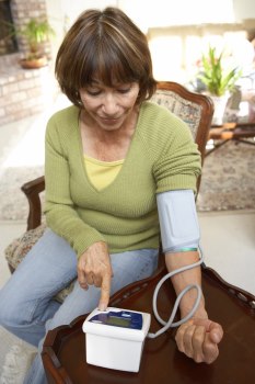 Middle aged woman taking her blood pressure with a home monitor.